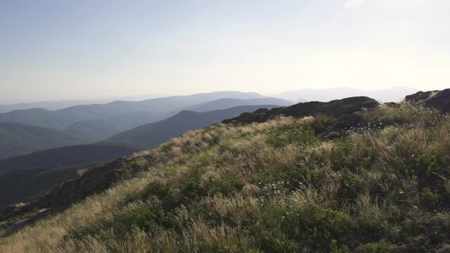 Pan shot of Stara planina mountains and Sliven Valley from a high point during late afternoon. Green slopes stretch far distance. Horizon. Balkan Mountains.