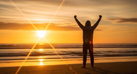 Fototapeta premium Man silhouette standing with raised arms on a beach at sunrise. Motivation and energy triumph. Person enjoying freedom with a bright sun flare.