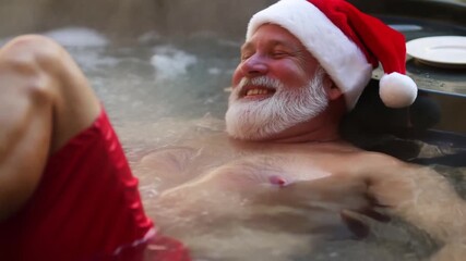 Santa Claus blissfully relaxing in a bubbling jacuzzi. The ultimate Christmas luxury and relaxation video for wellness ads.