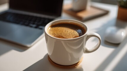 A cozy white coffee cup sits on a sleek desk beside a laptop, radiating warmth and inviting comfort into the workspace.