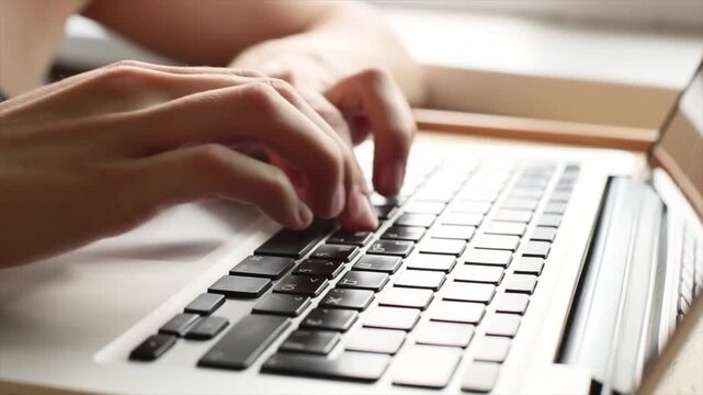 Close up of hands typing on laptop keyboard in soft natural light, modern workspace concept showing productivity, communication, remote work and digital technology environment