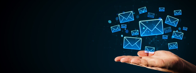 Digital email icons floating above open hand on dark background representing modern communication, technology and online messaging concept.
