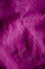 A full-frame abstract background featuring wrinkled magenta fabric with a visible woven texture. The surface is characterized by soft folds, crumpled creases, and deep shadows, creating a vibrant