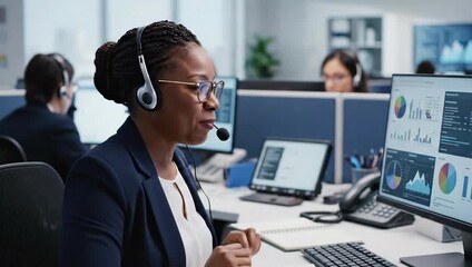 Smiling Black Woman in Navy Blazer and White Shirt Wearing Headset Points to Computer Screen with Charts in Modern Office - Powered by Adobe