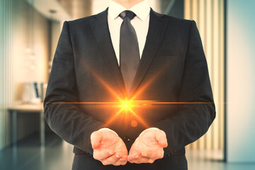 Businessman holding glowing light in hands symbolizing innovation and creativity in professional...
