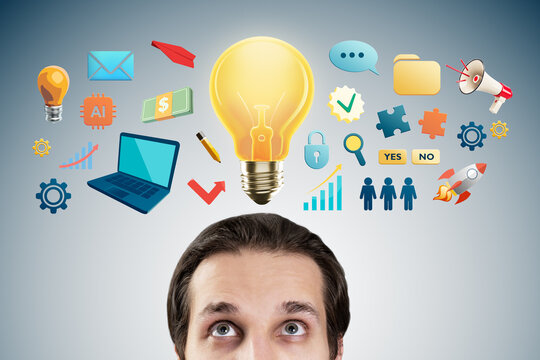 Man looking up at glowing lightbulb surrounded by colorful business and technology symbols on a gradient background representing creative ideas.