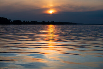 Sunset and its reflection in the water and waves of the reservoir