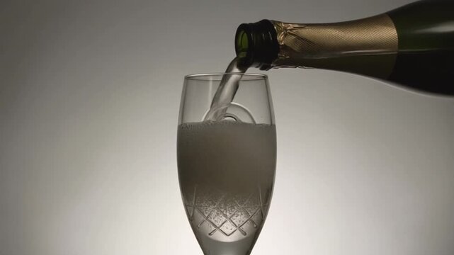 Glass engraved with the number 9. Champagne bottle fills the glass with alcohol. Celebrating milestone, anniversary or birthday