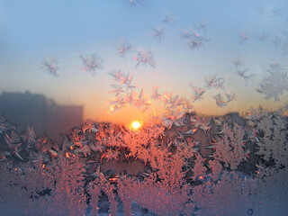 Beautiful ice pattern and sunlight on window glass, close-up natural winter background
