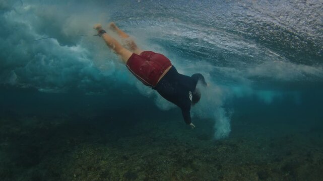 Surfer falls from the wave head first. Surfing in the Maldives. In water and underwater view of the surfer on the wave