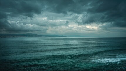 Obraz premium Wide shot of moody ocean under a stormy sky, distant land visible