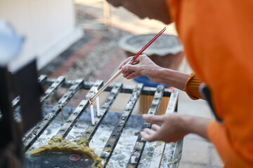 Focused man in orange clothing carefully applying oil to barbecue grill with brush. His concentration shows while he prepares for outdoor summer cooking and grilling