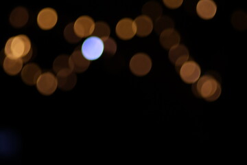 Warm abstract golden bokeh Christmas lights background, large defocused yellow circles on black, classic festive holiday decoration for greeting card, luxury backdrop or blurry night texture