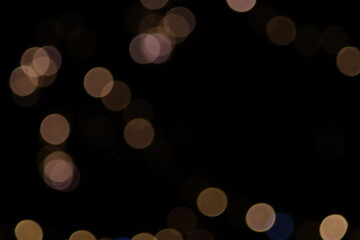 Warm abstract golden bokeh Christmas lights background, large defocused yellow circles on black, classic festive holiday decoration for greeting card, luxury backdrop or blurry night texture