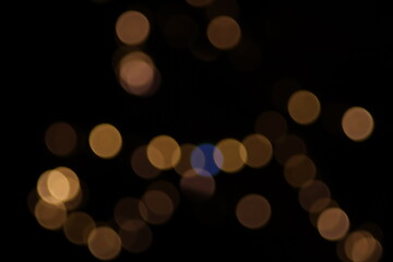 Warm abstract golden bokeh Christmas lights background, large defocused yellow circles on black, classic festive holiday decoration for greeting card, luxury backdrop or blurry night texture