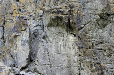 The image shows the Kargah Buddha, a large standing Buddha carved into a cliff face in the Kargah Nala, approximately 6 miles outside Gilgit City, Pakistan
