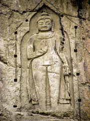 The image shows the Kargah Buddha, a large standing Buddha carved into a cliff face in the Kargah Nala, approximately 6 miles outside Gilgit City, Pakistan