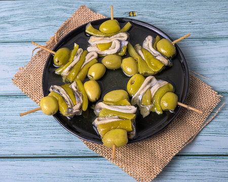 Traditional basque gilda skewer appetizer with anchovies olives and peppers on rustic wooden table