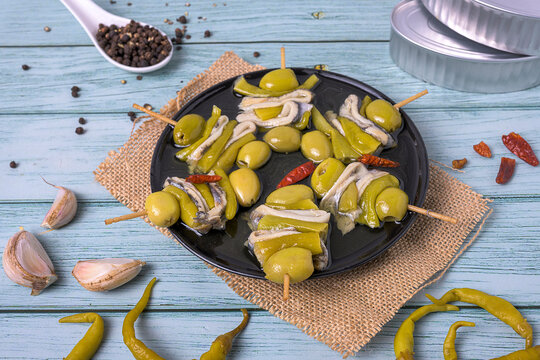 Traditional basque gilda skewer appetizer with anchovies olives and peppers on rustic wooden table