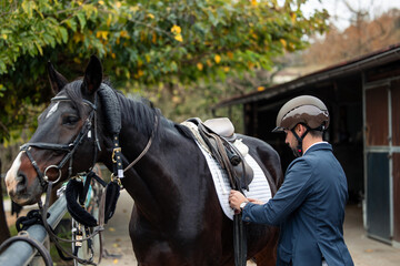 Man saddling horse preparing for equestrian sport training