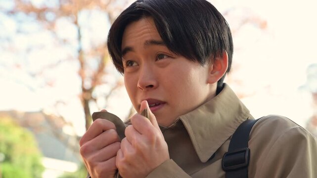 秋冬の紅葉の屋外で風邪をひいて寒気や悪寒、発熱や頭痛を感じるコートを着たビジネスマン動画