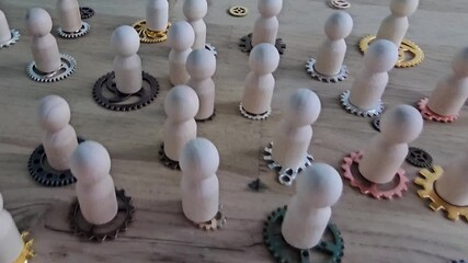 Wooden figures of people standing on interconnected gears. Teamwork, collaboration, and the interconnected nature of the work