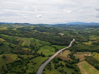 Aerial drone view of Highway winding through lush green mountains between Nan, Thailand. A scenic landscape of the road surrounded by tropical forest and a peaceful countryside