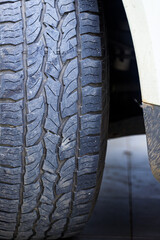 Closeup of a four-wheel drive pickup truck all-terrain tire showing worn tread patterns, dirt, and signs of rugged off-road use