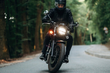 Naklejka premium Front view. Man in leather clothes on motorcycle is on the road