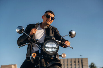 In cool sunglasses. Man is outdoors with his motorcycle