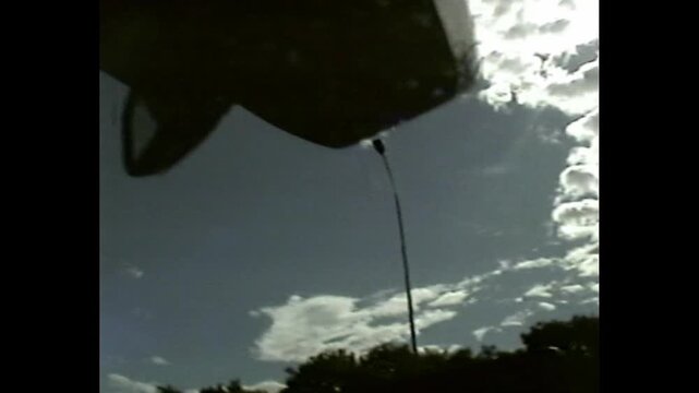 Man in driver's seat captured in dim light with grainy VHS-style visual and reflections