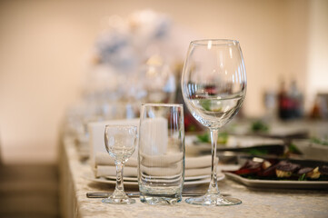Serving and setting table in a restaurant. Plate and glass, stack, wineglass, luxury rich decor. Wedding set up, dinner table reception. Birthday party, baptism, event. Closeup details of interior.