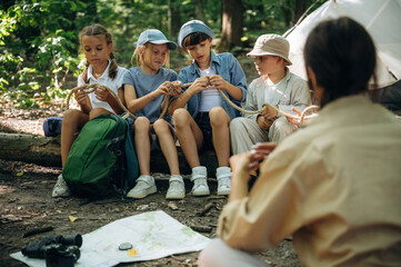 Teaching how to tie the knot. Woman is doing tour for group of kids in the forest