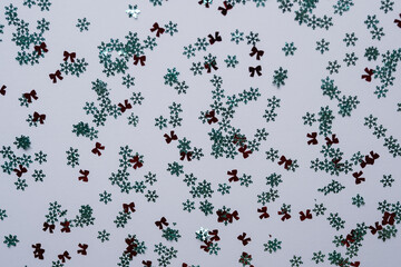 A crisp flat lay of sparkling silver snowflakes and vibrant red bows scattered evenly across a pure white background. Pattern for wrapping paper, textiles, and digital backgrounds.