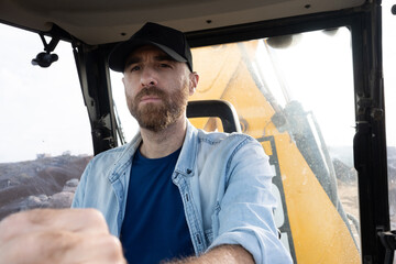 Young man driving a backhoe loader in the countryside