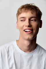 Smiling young man in a white tee with a relaxed pose, conveying approachable confidence and casual...