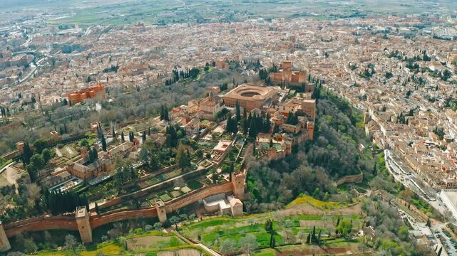 Aerial view historical Alhambra Palace at sun surrounded by Sierra Nevada mountains in Granada Spain old town palace complex with surrounding gardens Andalusia drone flying over famous palace fortress