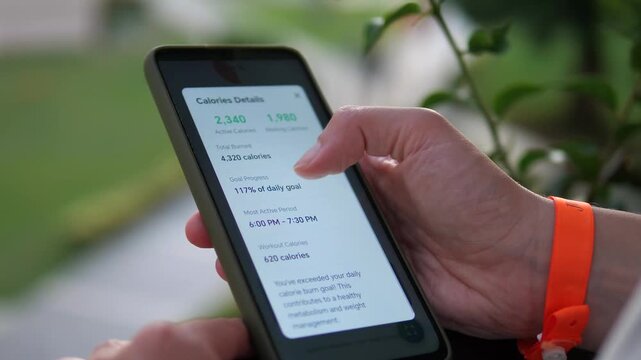 Womans hands on a sunny balcony, attentively checking a health and fitness app on her smartphone, focused on calorie intake data. Represents modern wellness, mindful living, diet tracking, and a