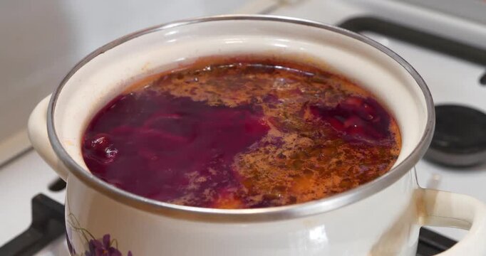 Ukrainian borscht is cooked on gas stove. Red Ukrainian borscht is boiling in saucepan. National dish of Ukraine. Main first course of Ukrainian cuisine. Cooking first courses