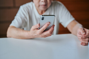 部屋でスマホを操作するシニア女性