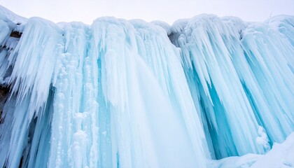 Vast natural formation of vibrant blue and white icicles hanging from a steep cliff face in winter