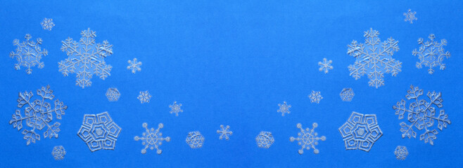 Merry Christmas and Happy New Year. Beautifyl banner with winter ornament of silver snowflakes on blue background. Christmas backdrop. Top view, copy space, flat lay, blank, closeup, mock up, panorama