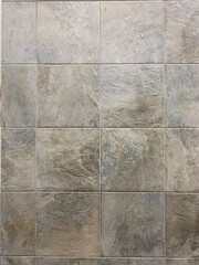 Gray stone-effect floor tiles in a grid pattern with natural texture and subtle brown and beige variations