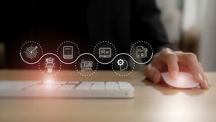 Close up of a person s hand using a computer mouse with a glowing digital interface overlay showing icons representing business and technology processes on a desk