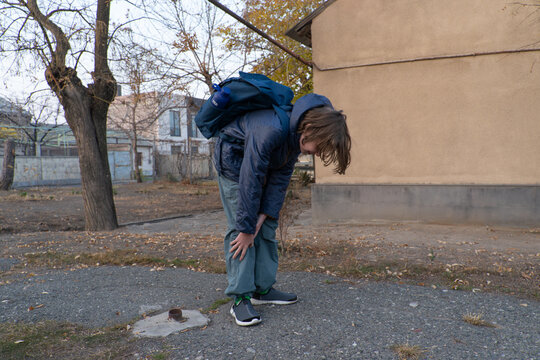 Tired schoolboy with a backpack bending over to rest. Exhausted child catching his breath