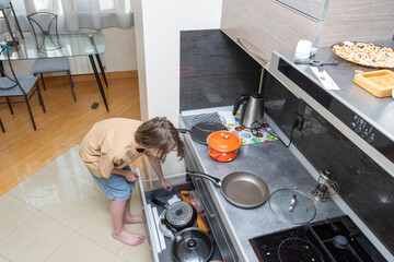 Person searching in a messy kitchen drawer for a pot. High angle view of domestic life