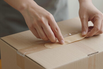 Person wrapping a cardboard box with adhesive tape.
