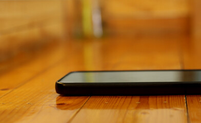 A smartphone placed on a wooden table in a caf&eacute;