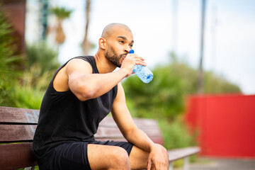 Man hydrating after workout on bench outdoors