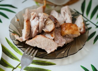 Close-up shot of chopped pieces of baked pork on a plate on a table